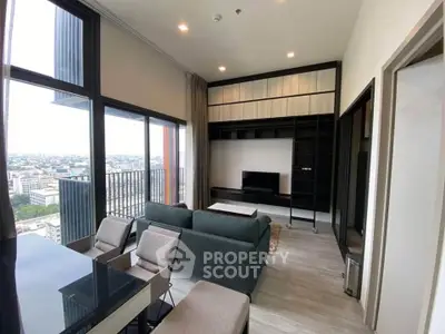 Modern living room with large windows and city view, featuring sleek furniture and built-in shelving.