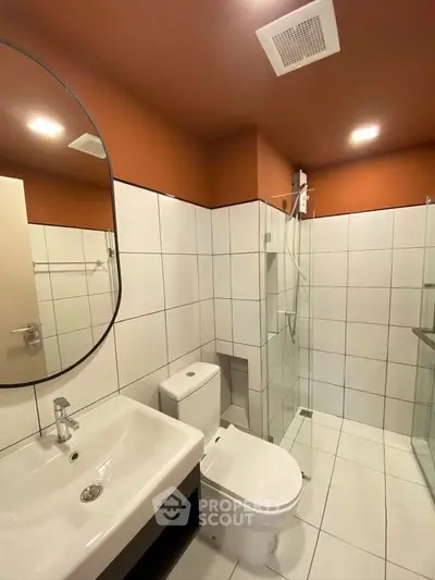 Modern bathroom with sleek design, featuring a glass shower, white tiles, and stylish fixtures.