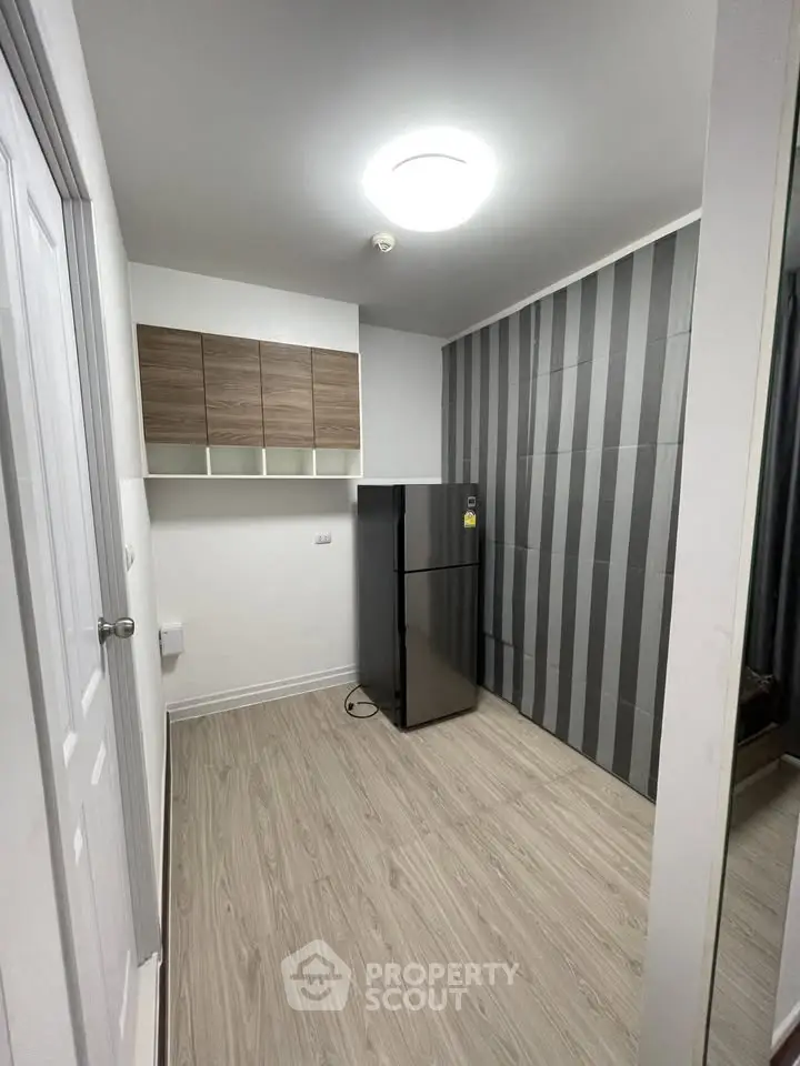 Modern kitchen with sleek fridge and stylish cabinetry in compact space.
