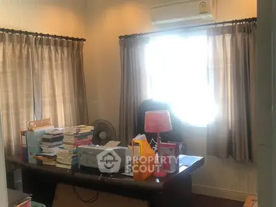 Cozy study room with desk, books, and natural light through window.