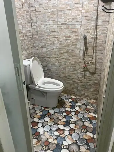 Modern bathroom with stone tile flooring and wall-mounted shower in a cozy setting.