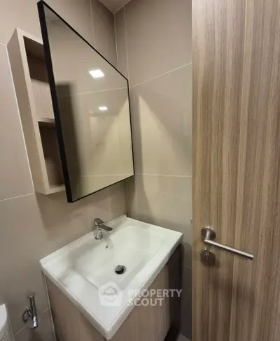 Modern bathroom with sleek sink and large mirror in contemporary design.