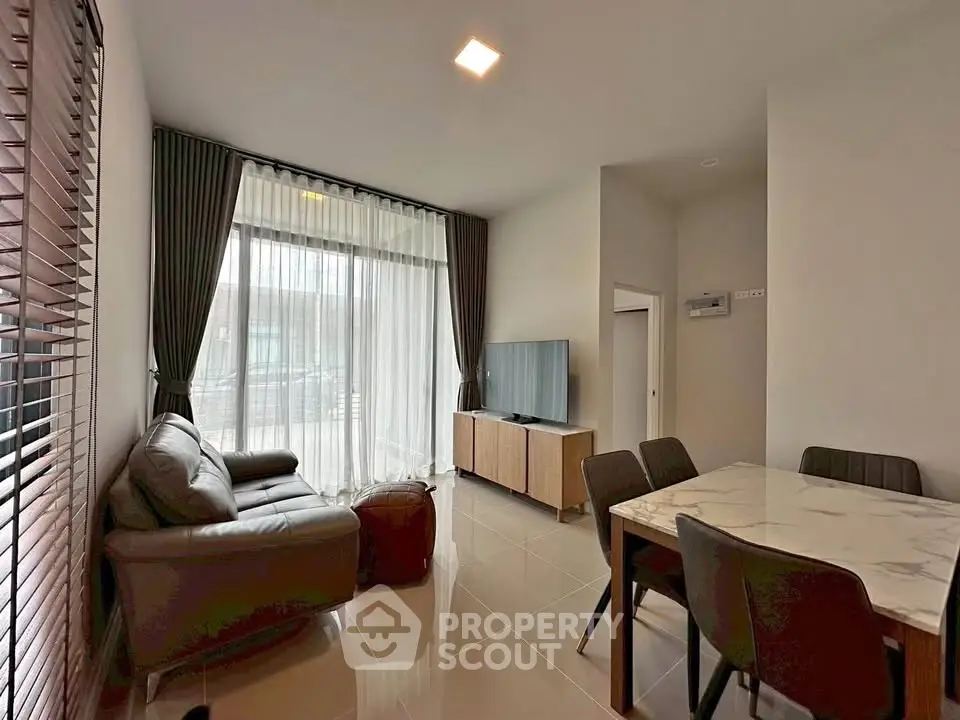 Modern living room with sleek furniture and large window, perfect for relaxation.