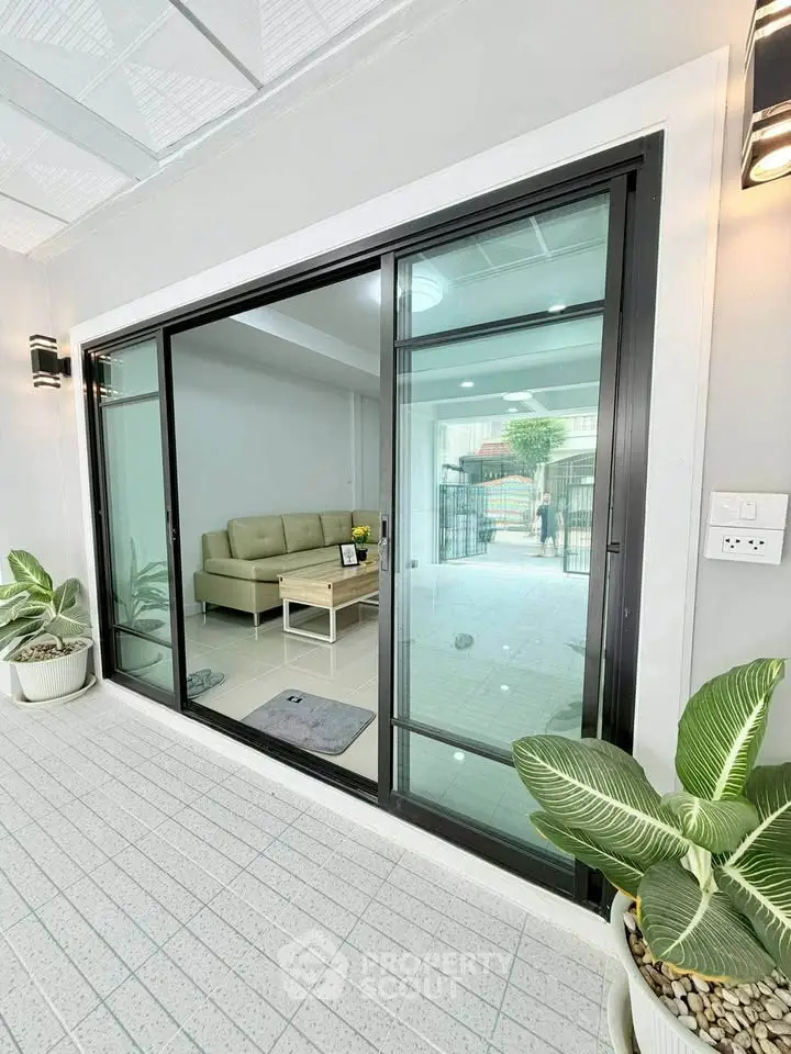 Modern living room with sliding glass doors and stylish indoor plants, offering a seamless indoor-outdoor transition.