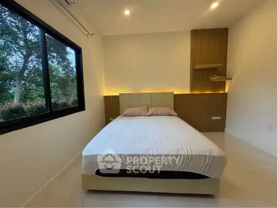 Modern bedroom with large window and stylish headboard, offering serene views and cozy ambiance.