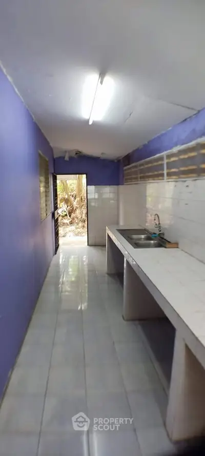 Spacious kitchen with open layout and natural light, featuring a sleek countertop and vibrant wall color.