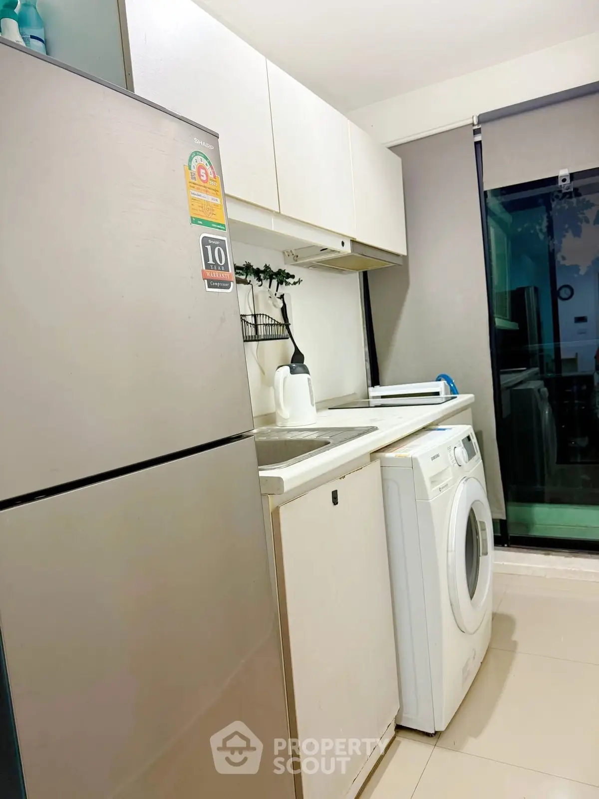 Modern kitchen with sleek appliances including fridge and washing machine, bright and functional space.