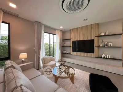 Modern living room with stylish decor and large TV, featuring a cozy sofa and elegant shelving.