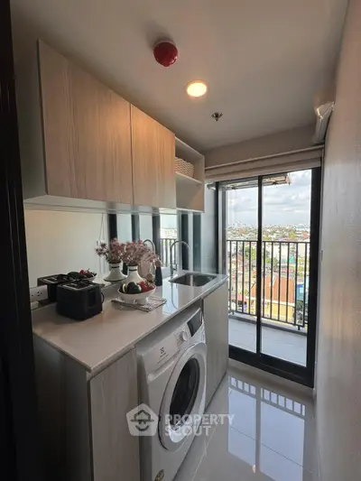 Modern kitchen with washing machine and balcony view in high-rise apartment