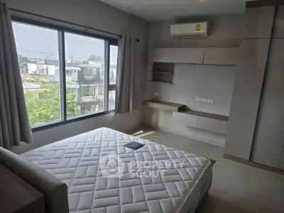 Spacious bedroom with large window and built-in storage in modern apartment