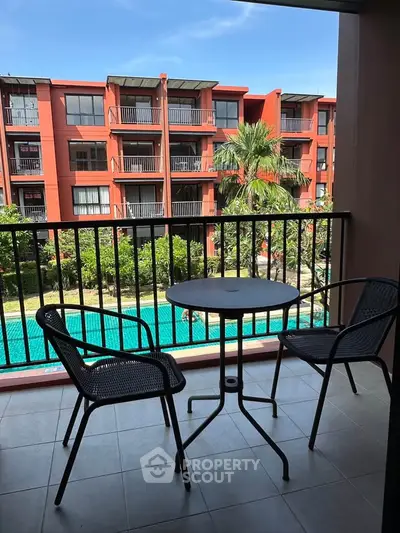 Charming balcony view overlooking pool and lush greenery in modern apartment complex.