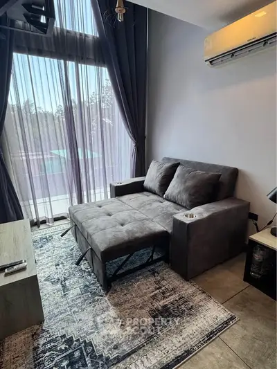 Modern living room with stylish sofa, air conditioning, and large window with elegant curtains.
