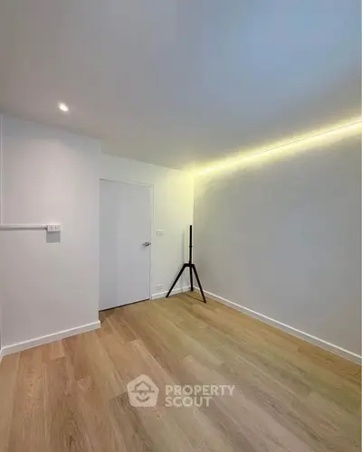 Minimalist empty room with wooden flooring and modern lighting