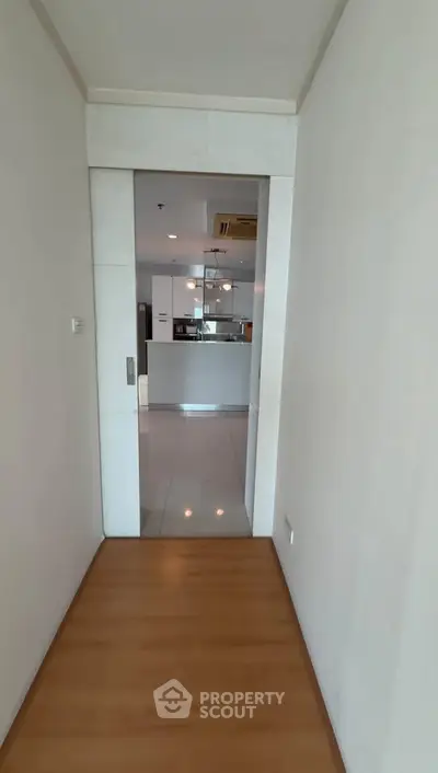 Modern apartment hallway leading to a sleek kitchen with open layout and contemporary design.
