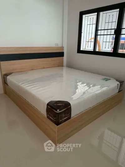Spacious bedroom with modern bed frame and large window for natural light.