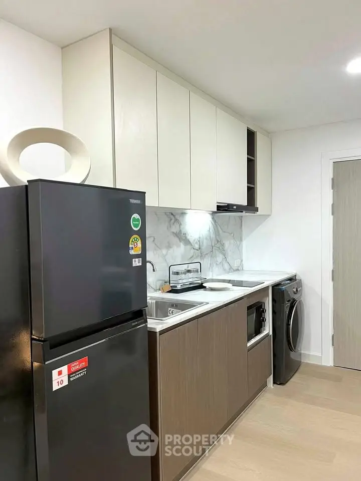 Modern kitchen with sleek appliances and stylish cabinetry in a compact layout.