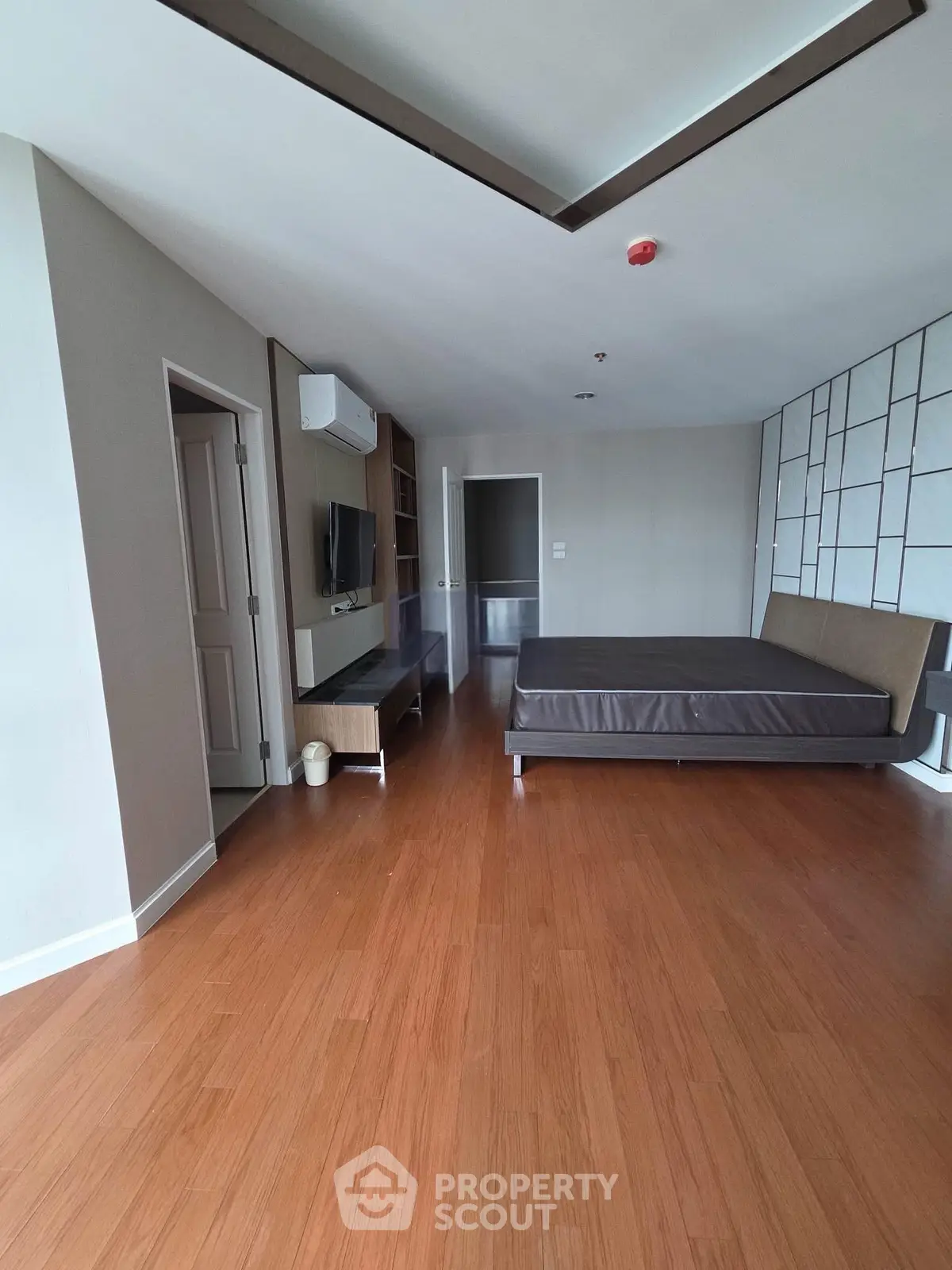 Spacious modern bedroom with wooden flooring and stylish decor
