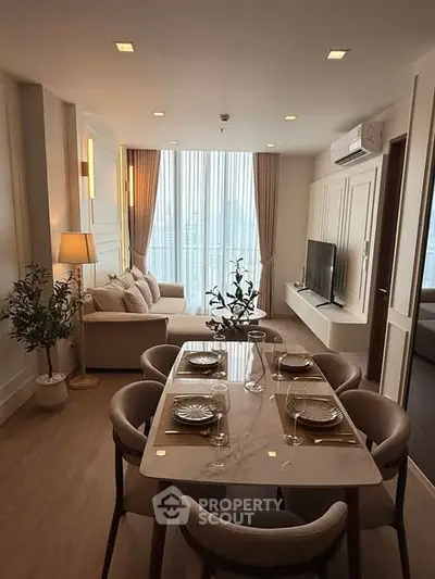 Elegant living room with dining area, modern decor, and large windows offering natural light.
