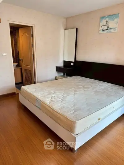 Spacious bedroom with wooden flooring and modern decor in a stylish apartment.