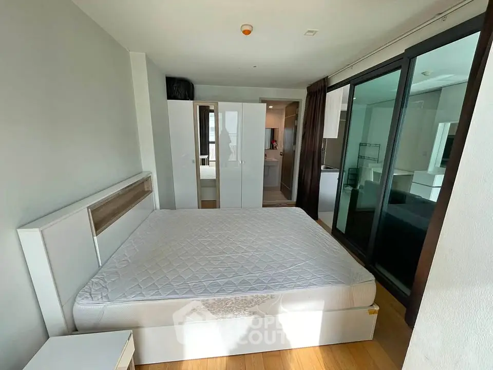 Spacious bedroom with modern furnishings and ample natural light, featuring a large bed and wardrobe.
