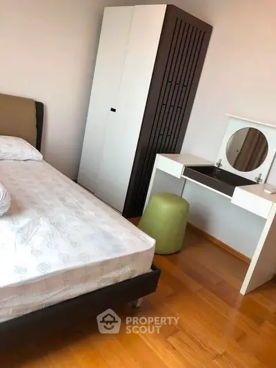 Modern bedroom with stylish furniture and wooden flooring, featuring a sleek wardrobe and vanity desk.