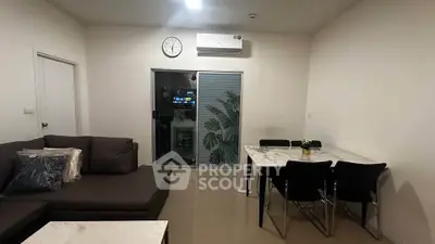 Modern living room with sleek furniture and dining area, featuring a wall-mounted air conditioner.