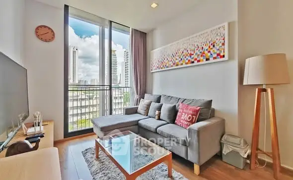 Modern living room with large windows and city view, featuring a cozy gray sofa and stylish decor.