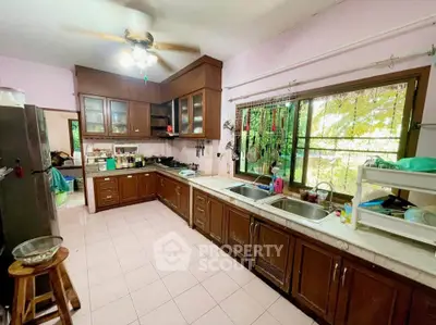 Spacious kitchen with wooden cabinets and large window, perfect for culinary enthusiasts.