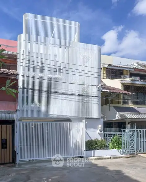 Modern white facade of a contemporary townhouse with unique vertical slats design.