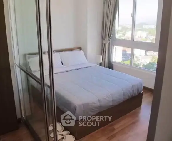 Cozy bedroom with large window offering a stunning city view, featuring a comfortable bed and elegant decor.