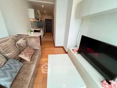 Modern living room with cozy sofa and TV, open layout leading to kitchen area.