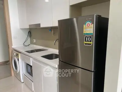 Modern kitchen with sleek appliances including fridge, washing machine, and electric stove in a compact layout.