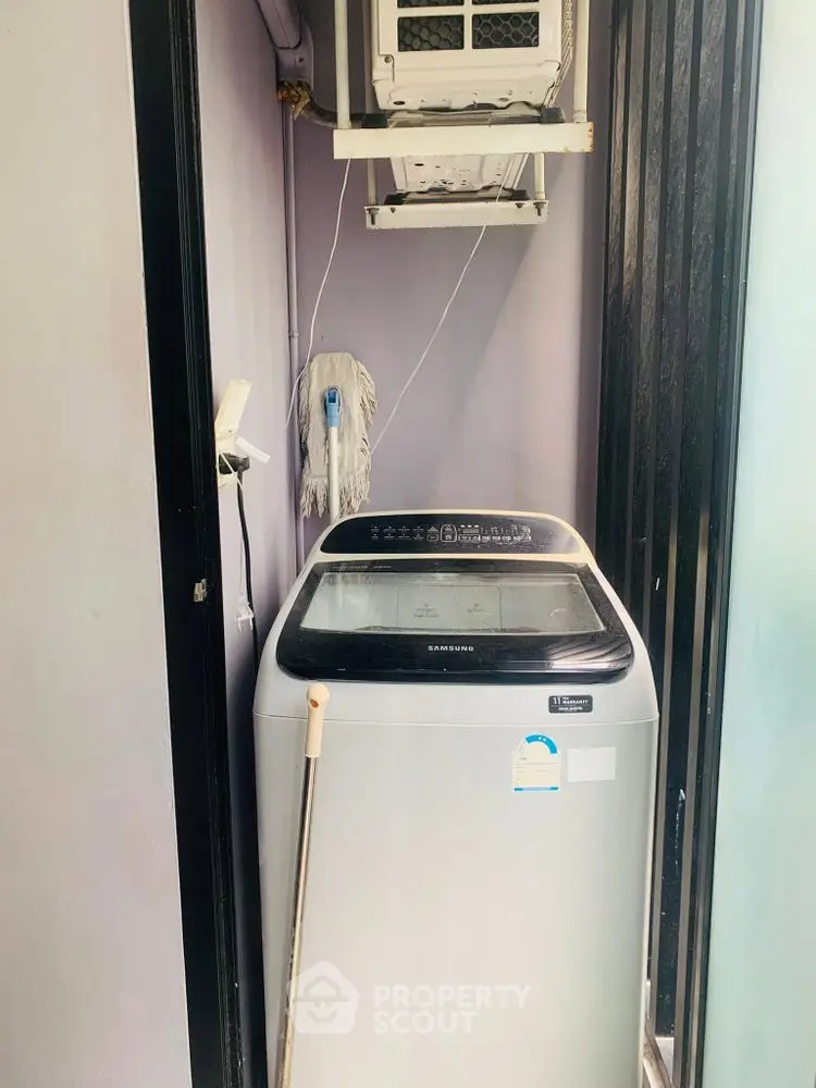 Compact laundry area with washing machine and air conditioning unit in modern home.