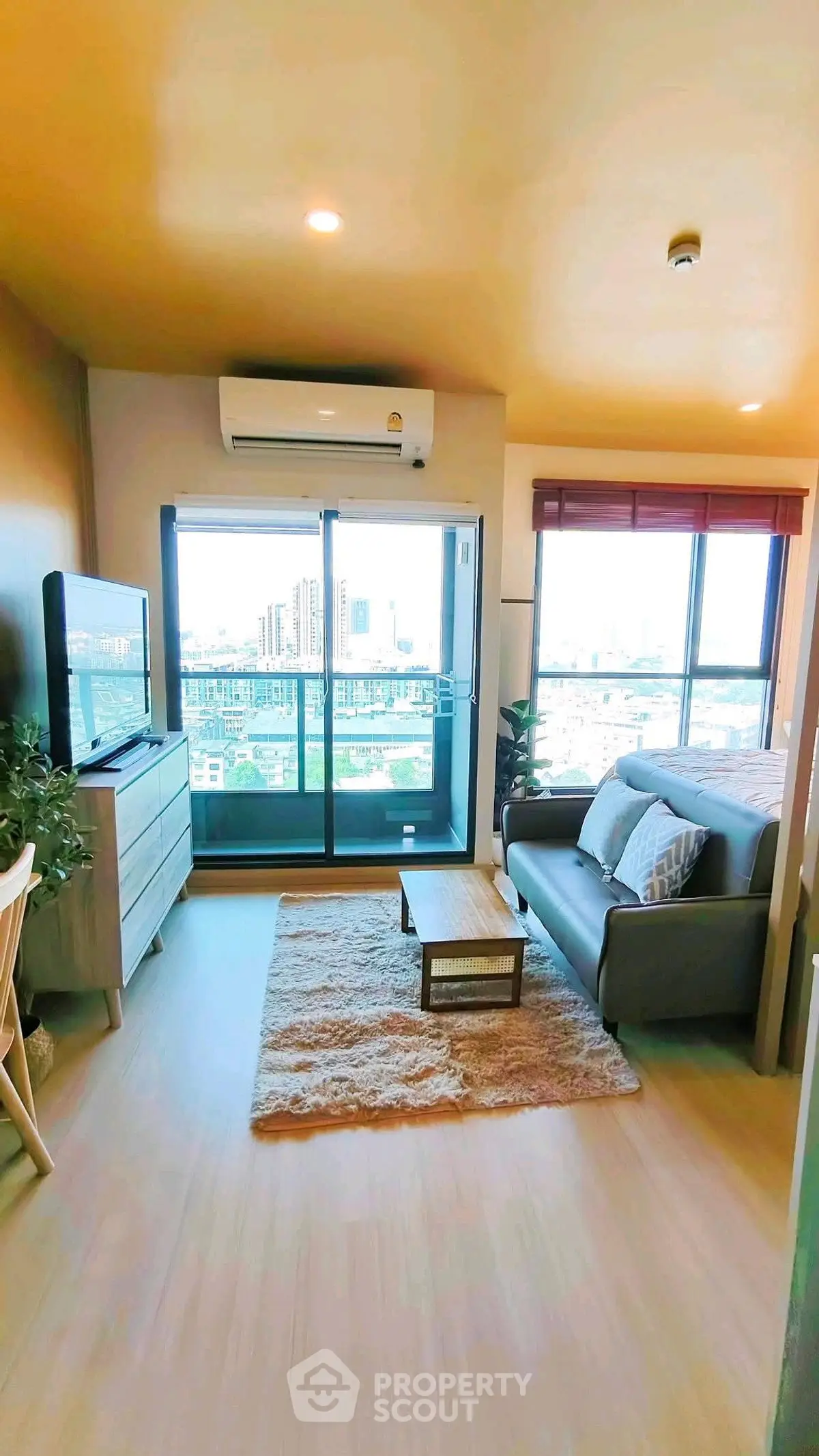 Modern living room with city view, cozy sofa, and stylish decor in a high-rise apartment.