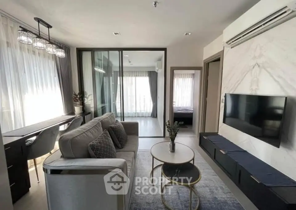 Modern living room with stylish decor and natural light, featuring a cozy sofa and wall-mounted TV.