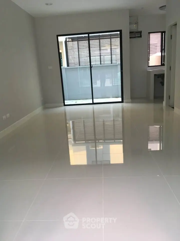 Spacious modern living room with glossy tiled floors and large sliding glass doors leading to a balcony.