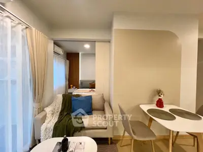 Modern open-plan living room with cozy sofa and dining area, featuring elegant decor and natural light.