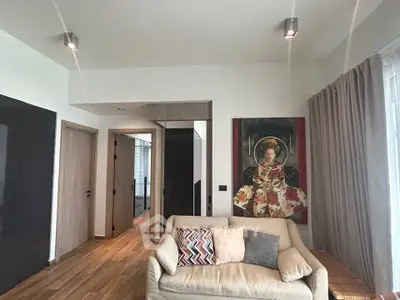 Modern living room with stylish decor and cozy seating area, featuring elegant wooden flooring and contemporary artwork.