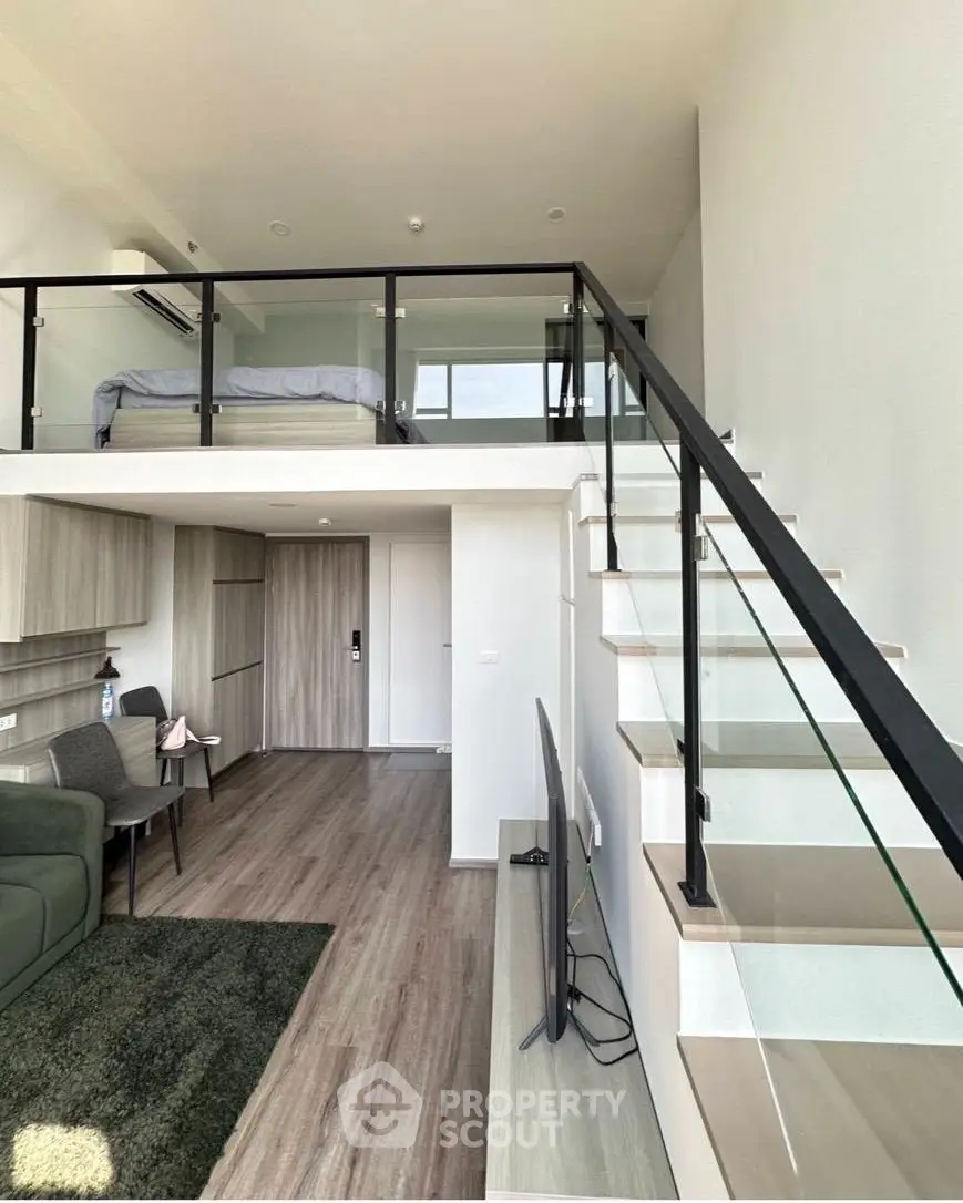 Modern loft apartment with mezzanine bedroom and stylish open living area, featuring sleek glass railing and contemporary decor.