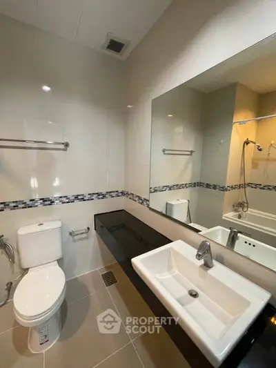 Modern bathroom with sleek fixtures and large mirror in a contemporary home.