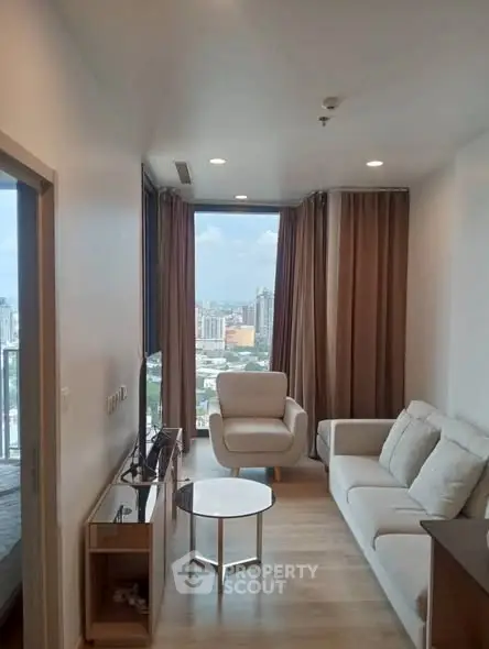 Modern living room with city view, featuring sleek furniture and large windows.