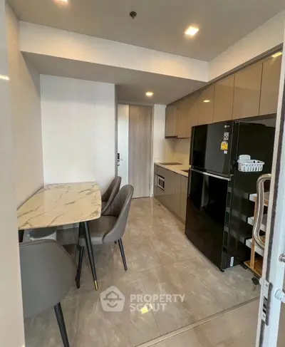 Modern kitchen with sleek appliances and marble dining table in a stylish apartment.