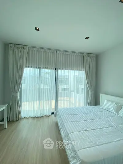 Spacious bedroom with large windows and elegant curtains in modern apartment