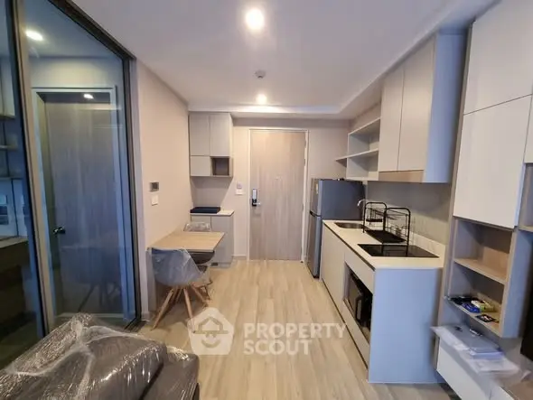 Modern compact kitchen with sleek cabinetry and integrated appliances in a cozy apartment.