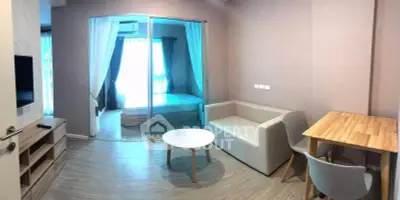 Modern apartment interior with cozy living room and bedroom separated by glass doors, featuring stylish furniture.
