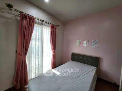 Cozy bedroom with pink accents and natural light, perfect for relaxation.