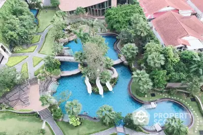 Luxurious aerial view of resort-style swimming pool with lush greenery and elegant landscaping.