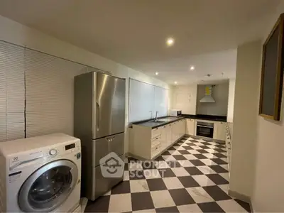 Spacious kitchen with modern appliances and checkered flooring, featuring a washing machine and stainless steel fridge.