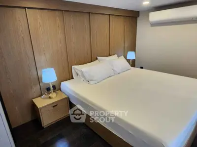 Modern bedroom with wooden accents and cozy lighting, featuring a comfortable bed and sleek air conditioning.