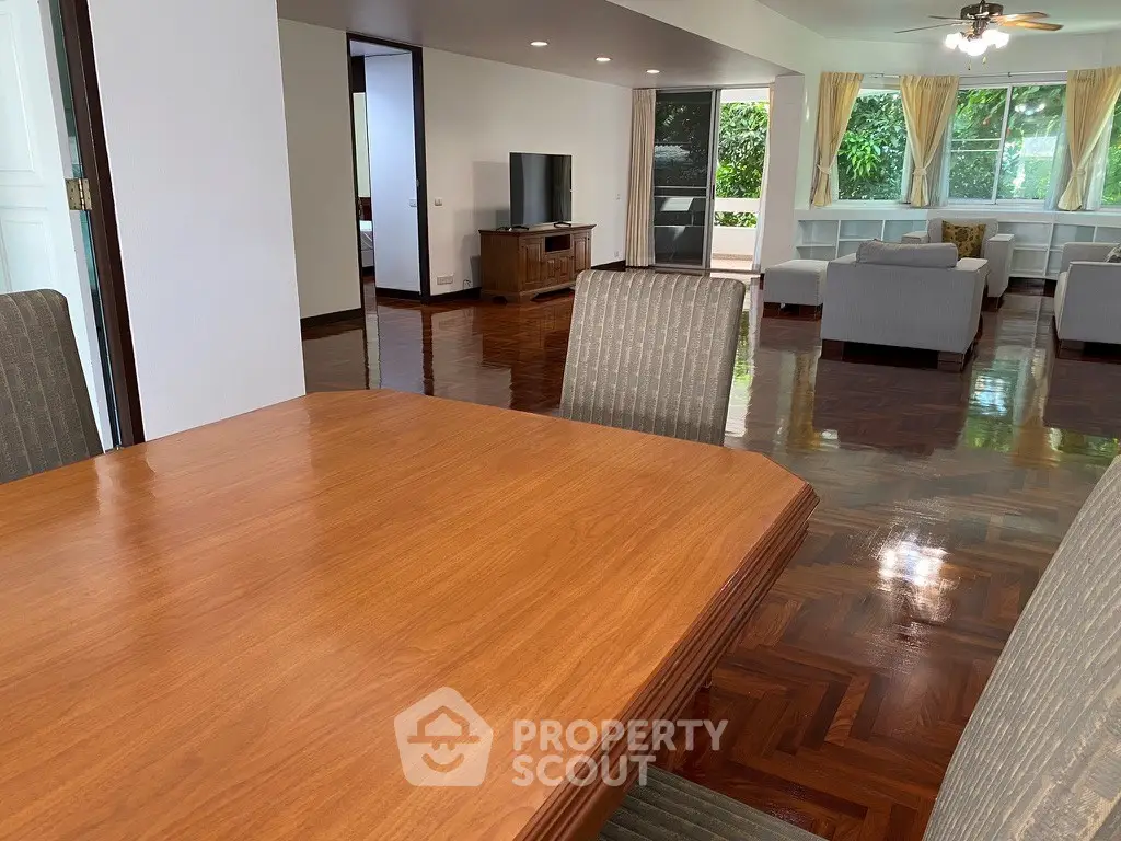 Spacious open-plan living room with elegant wooden flooring and modern furniture, perfect for family gatherings.